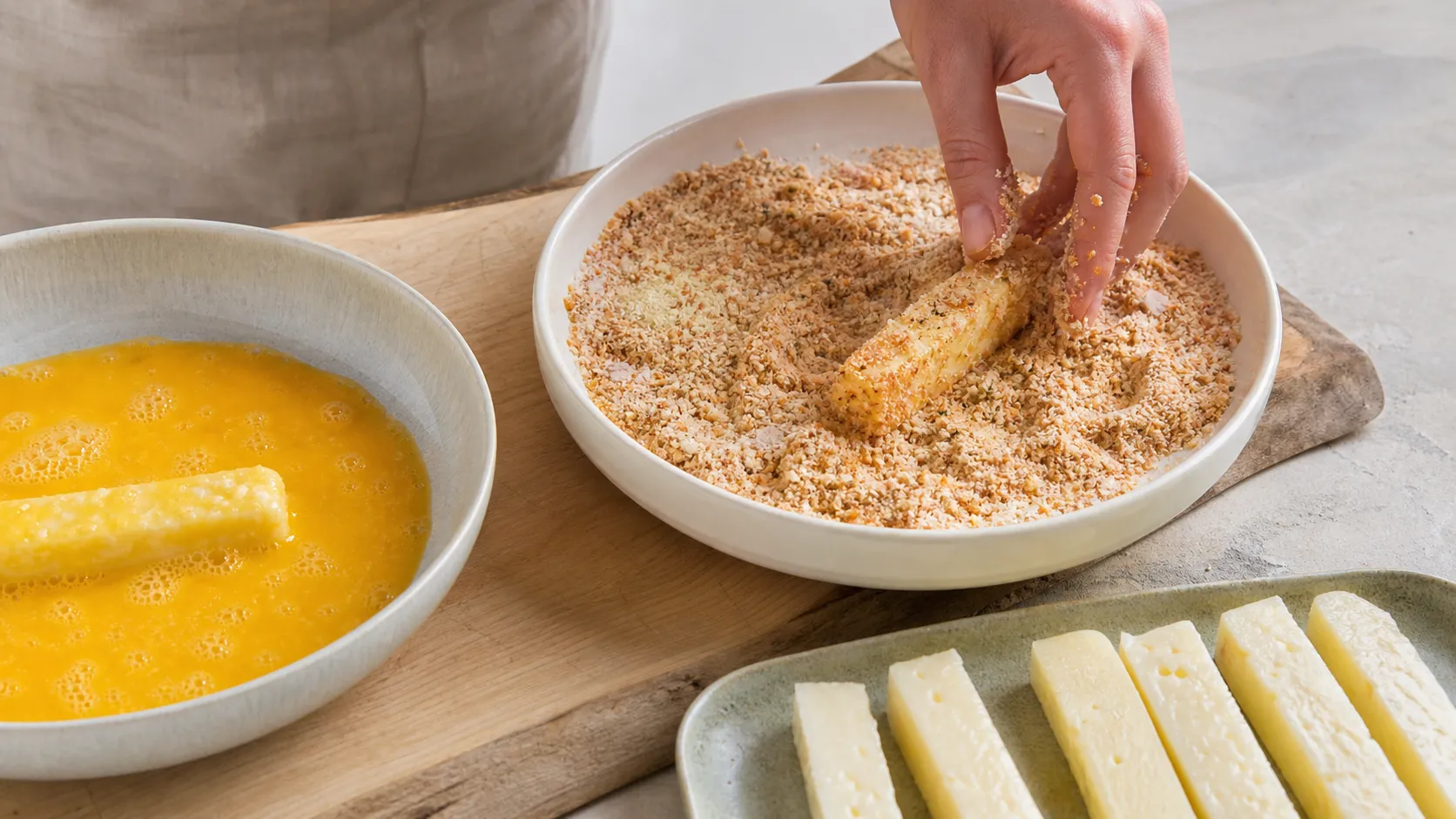 Halloumi sticks being turned in egg and almond flour coating