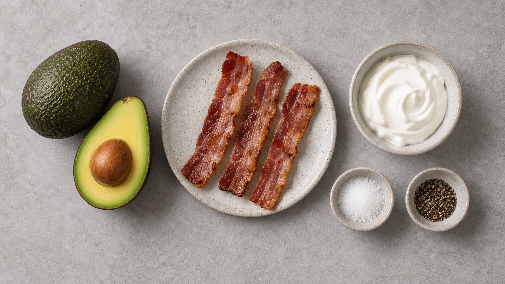 Ingredients for keto avocado bacon sour cream bowl with avocado, breakfast bacon, sour cream, salt and pepper