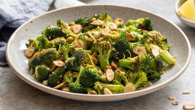 Keto broccoli with brown almond butter, lemon zest, and toasted almonds in a bowl