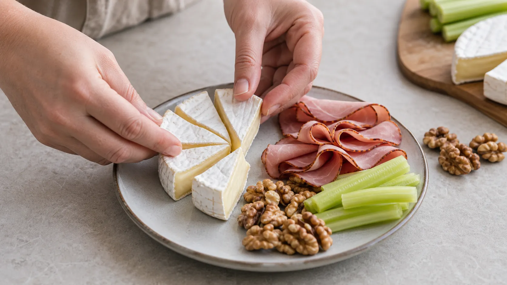 Camembert, walnuts, Black Forest ham and celery sticks being arranged on a plate