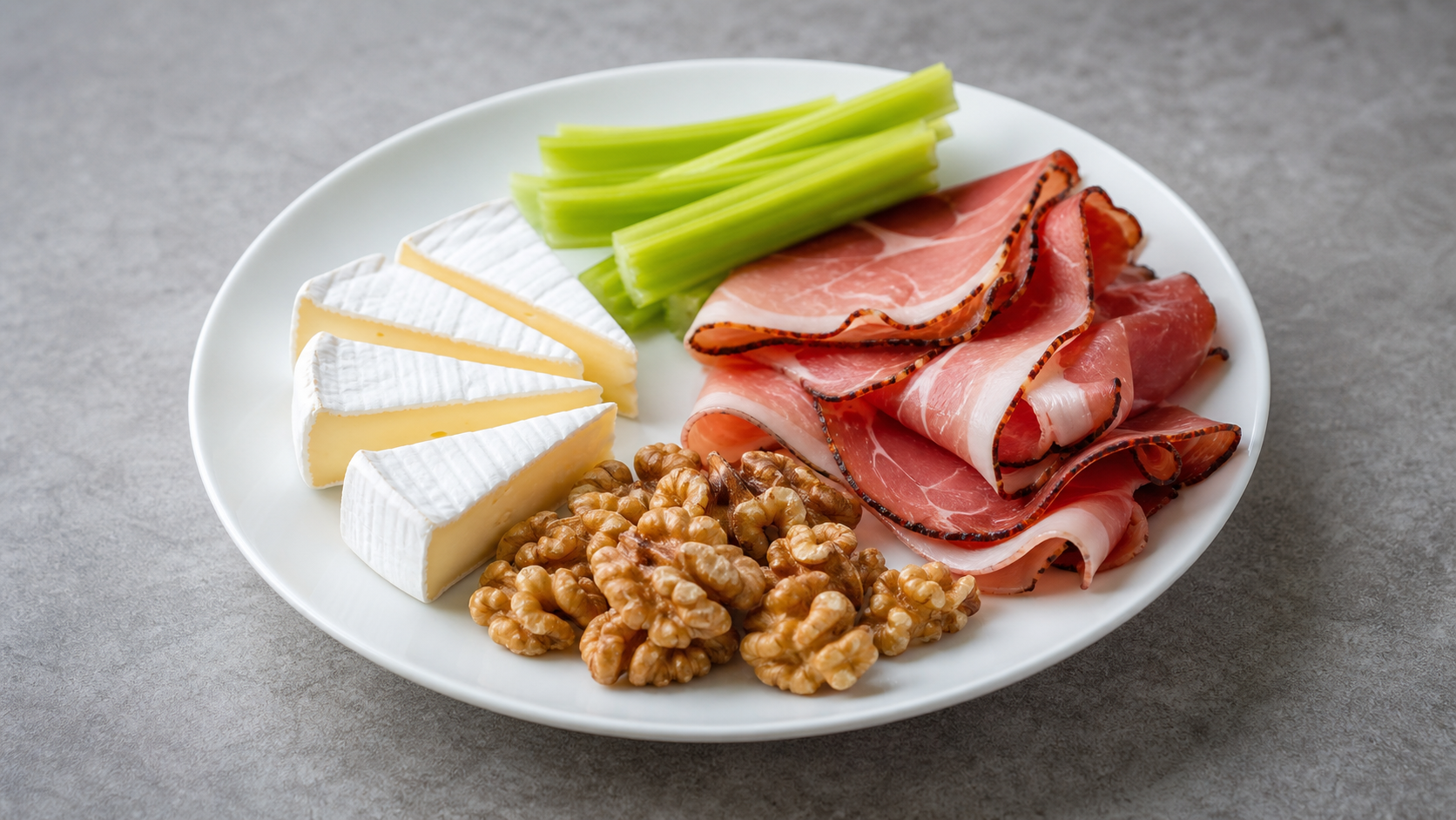 Keto breakfast plate with Camembert, walnuts, Black Forest ham and celery sticks