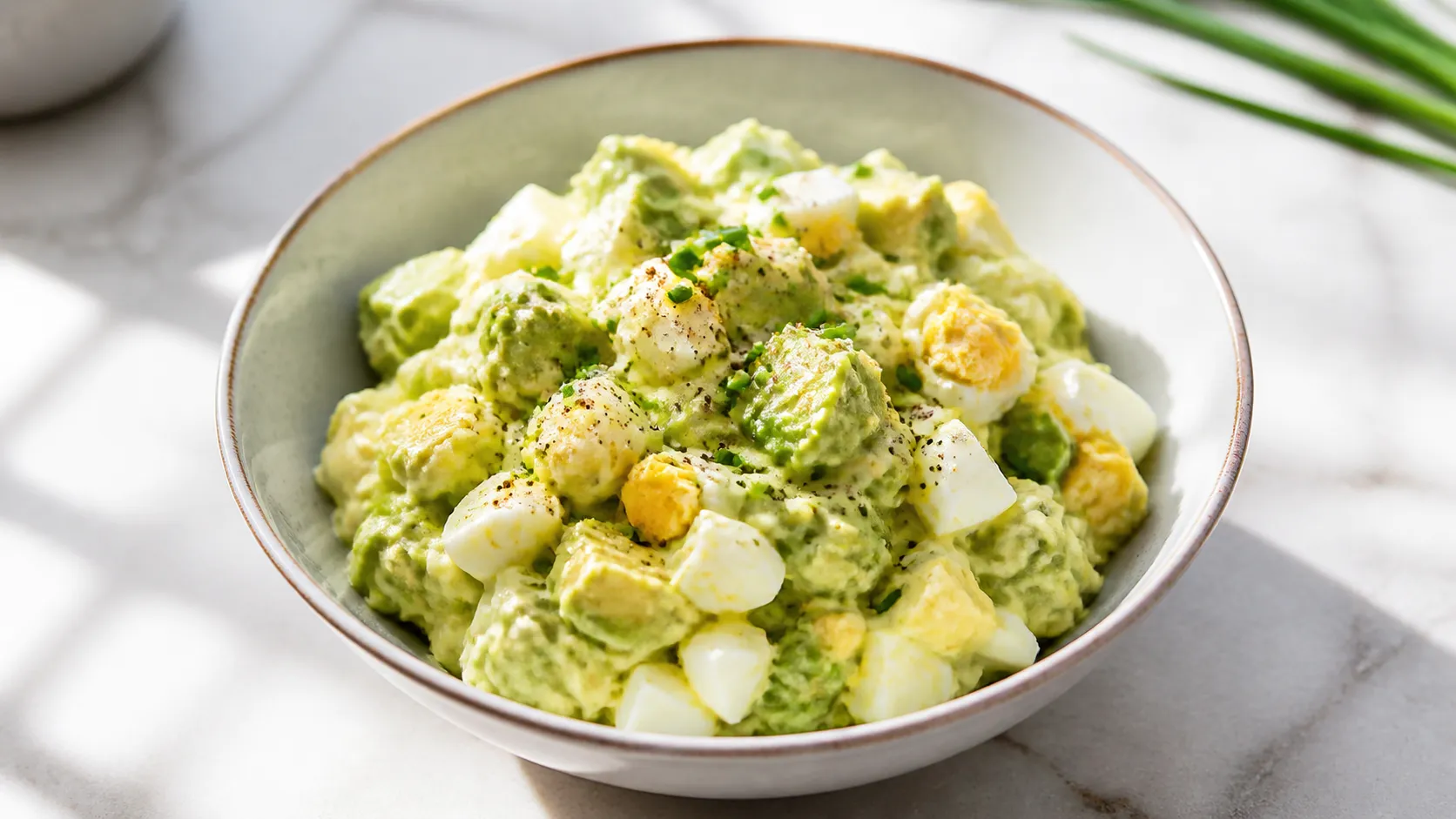 Keto egg avocado salad in a bowl with chives and mustard