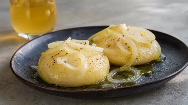 Handkase cheese with apple wine marinade on a plate with onion rings, olive oil and pepper