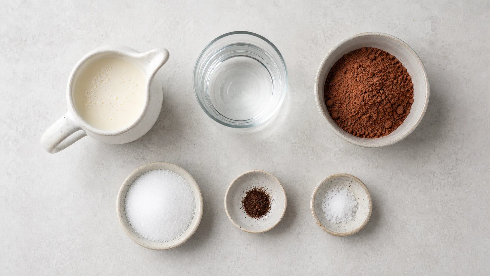 Flat lay of ingredients for keto hot chocolate with cream, water, unsweetened cocoa, erythritol, vanilla and salt