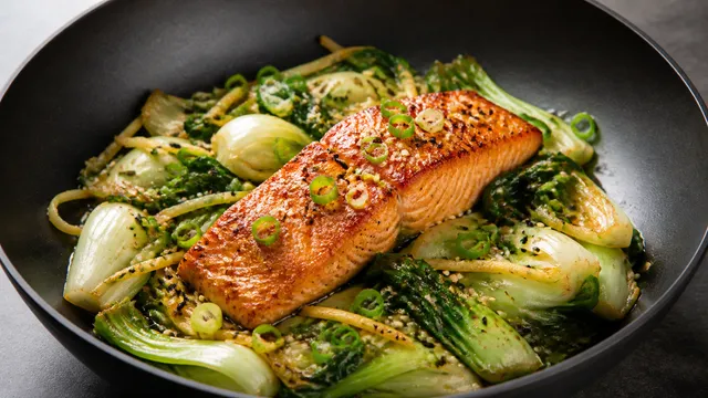 Keto salmon fillet on bok choy with ginger, sesame seeds, tamari and spring onion