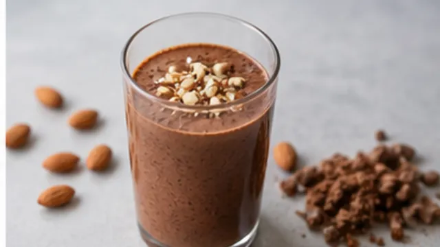 Keto almond butter cocoa smoothie in a glass topped with chopped almonds and cocoa powder