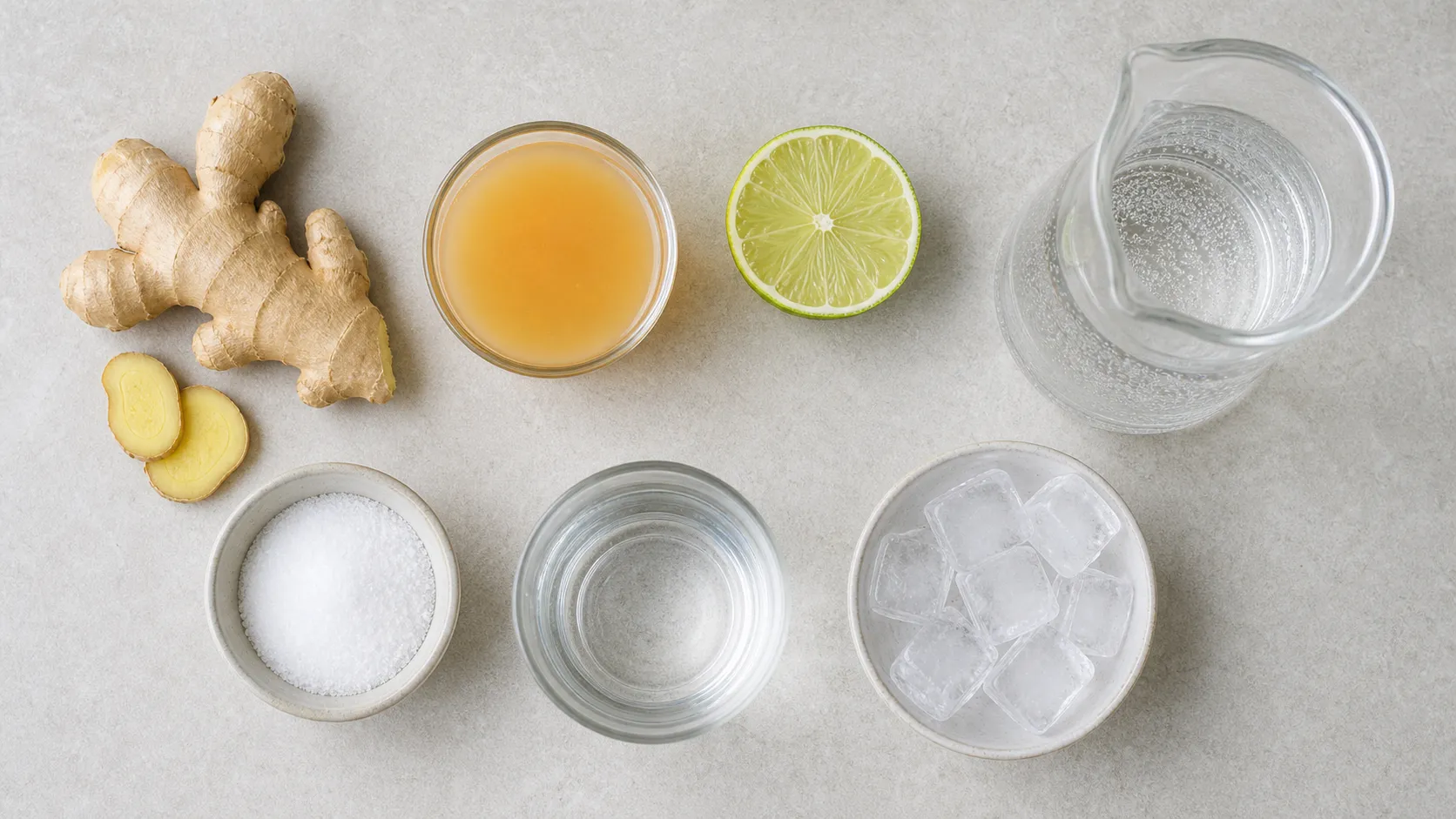 Flatlay of ingredients for keto switchel with ginger, apple cider vinegar, lime, erythritol, sparkling water and ice cubes