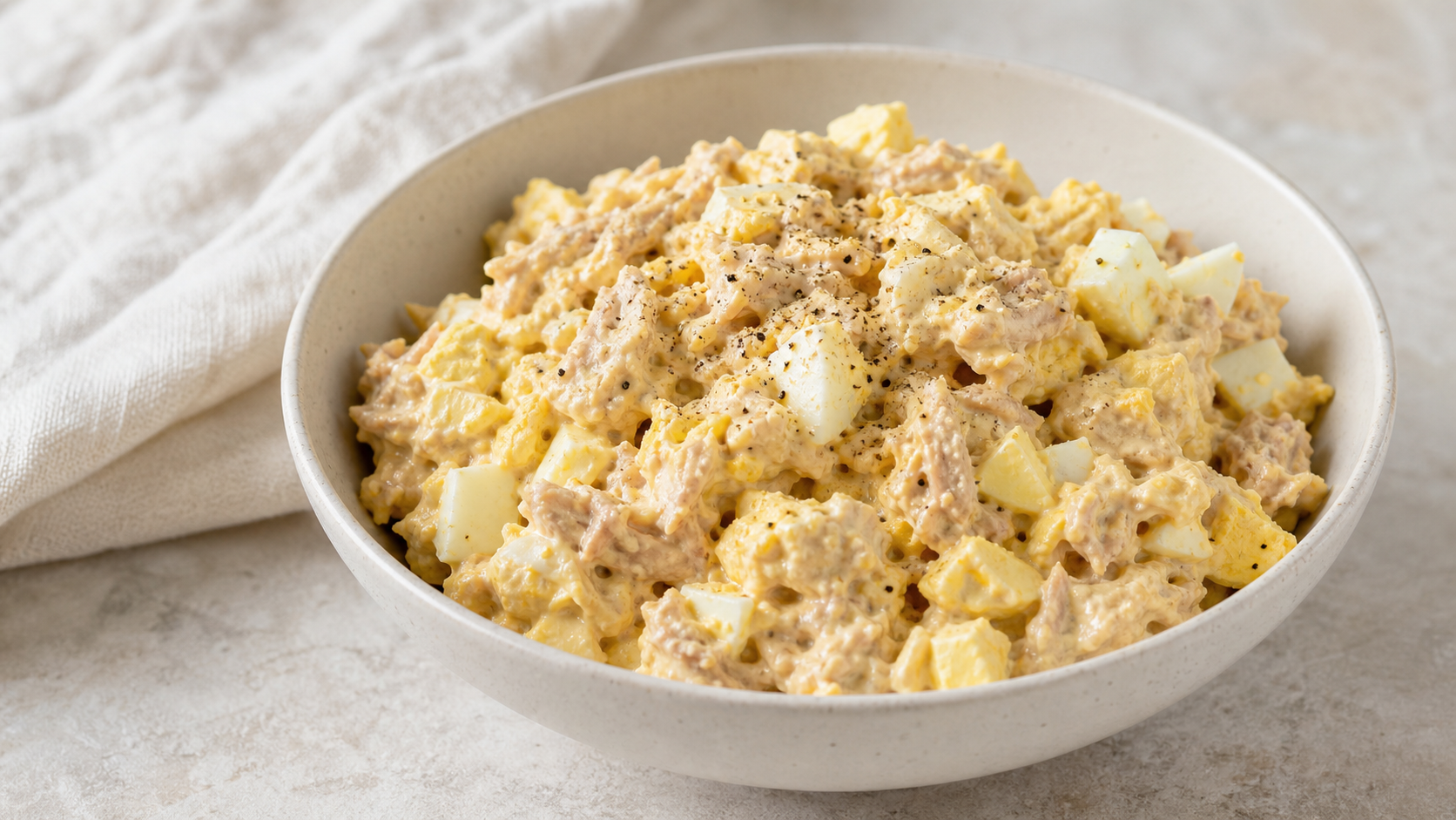 Keto tuna egg salad in a bowl with mayo, mustard and pepper