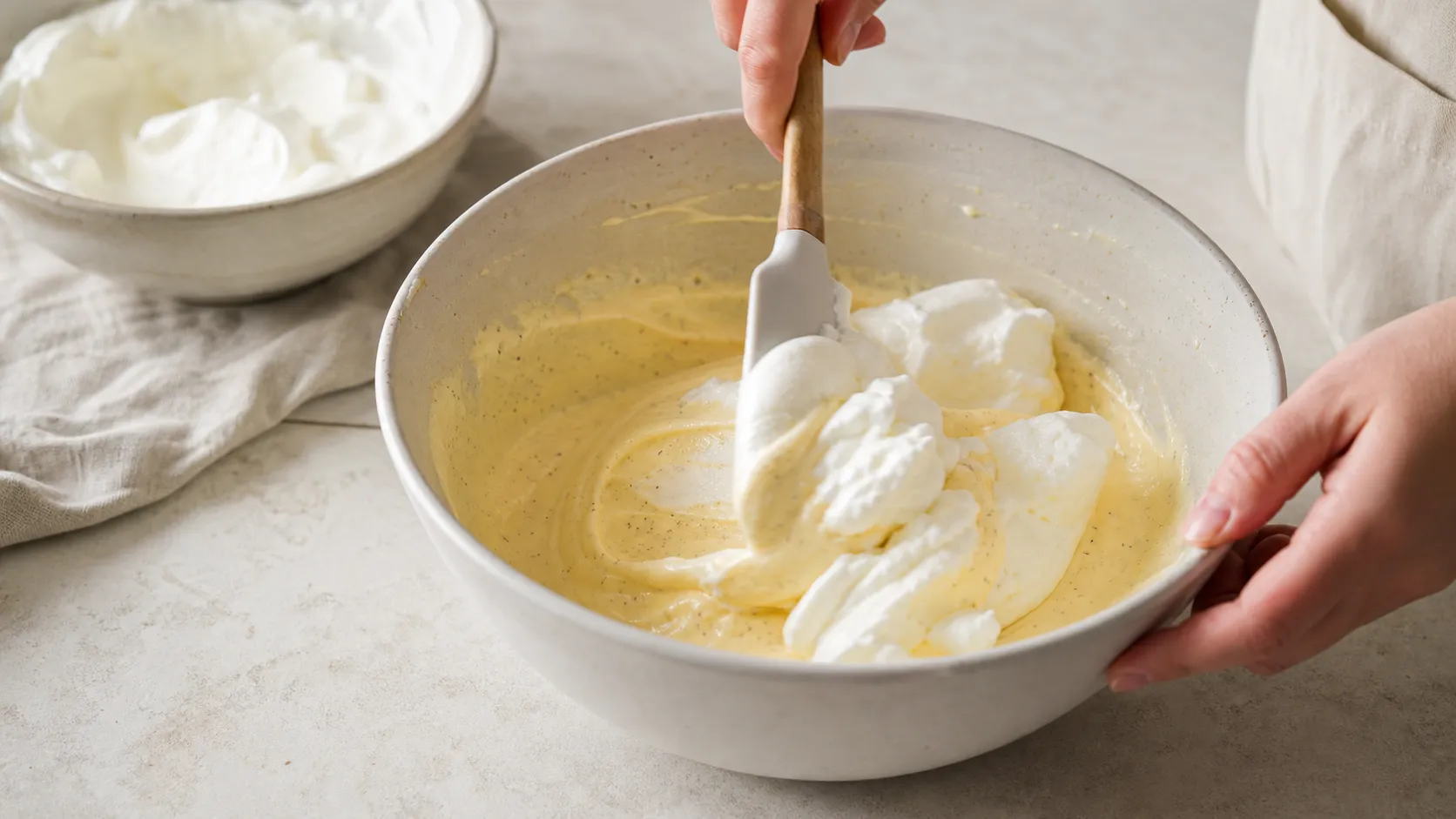 Whipped cream being folded into the cooled egg yolk mixture