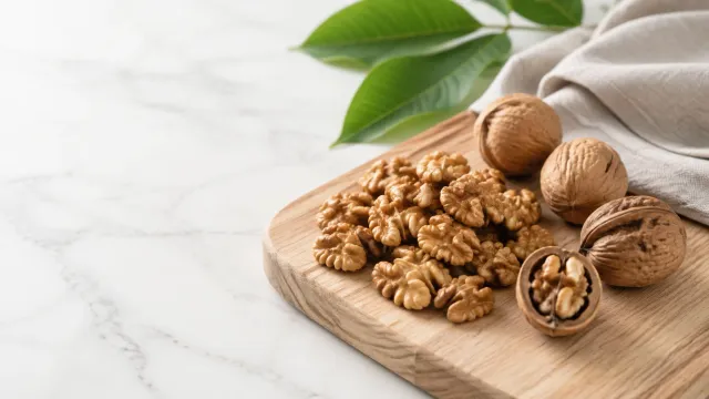 Keto food: walnuts in the shell and shelled walnut halves on a wooden board
